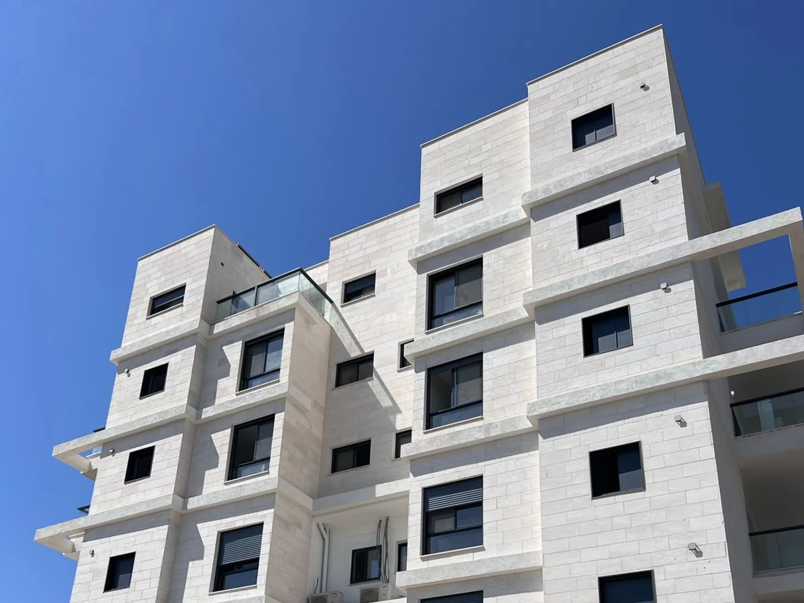 בניין מגורים בחיפוי אבן עם מערכות אלומיניום כהות