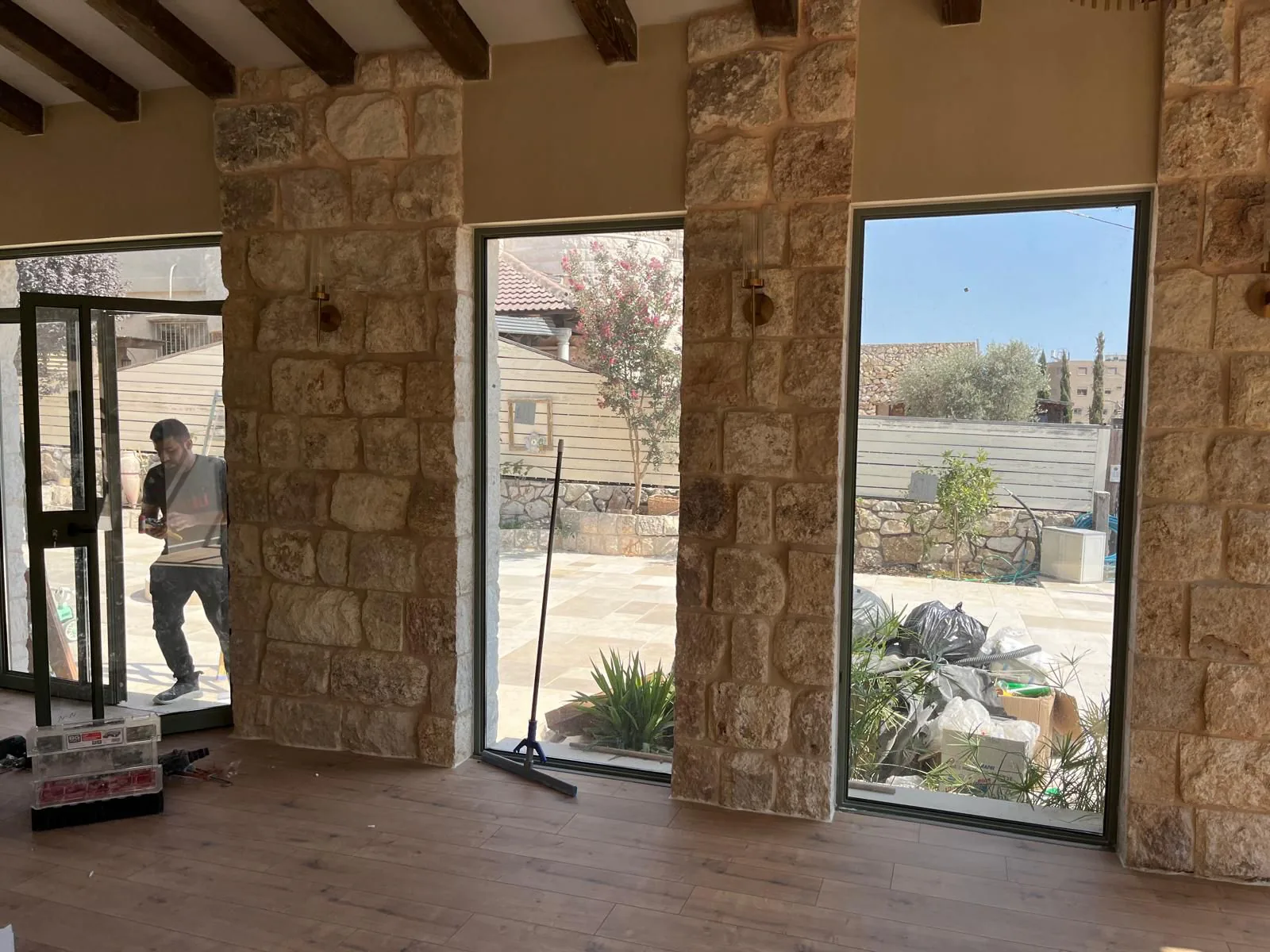 חלל מחופה אבן עם פתחים גבוהים מאלומיניום כהה ודלת זכוכית במהלך התקנה