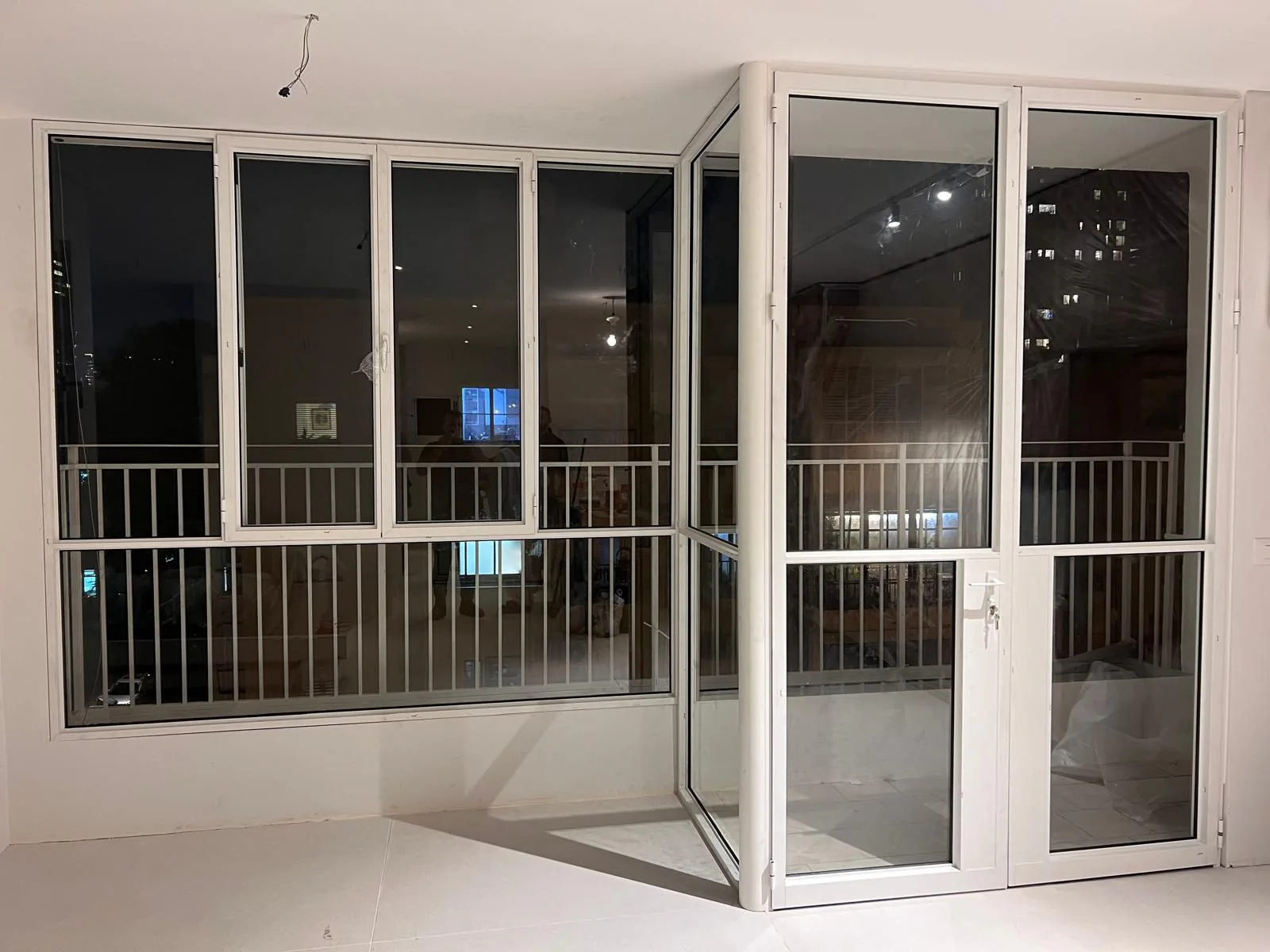 מערכת חלונות ודלת זכוכית מאלומיניום לבן הפונה למרפסת בשעת לילה
